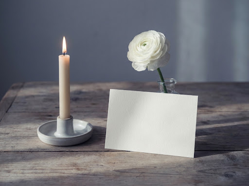 A candle, single flower and card arranged for remembrance